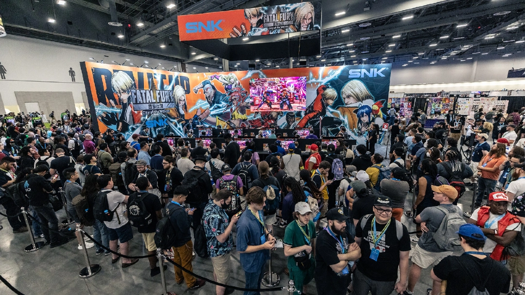 Público reunido em frente ao estande da SNK na Evo, com destaque para o banner de Fatal Fury: City of the Wolves e uma tela exibindo gameplay ao vivo.