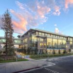 Sede da Netflix em Los Gatos, Califórnia, ao entardecer, com fachada de vidro refletindo o céu.