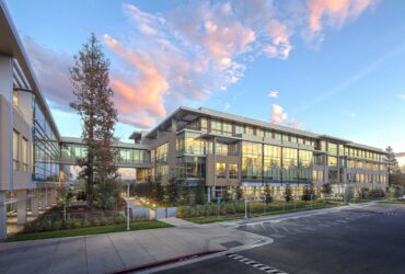 Sede da Netflix em Los Gatos, Califórnia, ao entardecer, com fachada de vidro refletindo o céu.