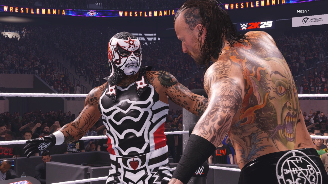 Dois lutadores se encaram no ringue durante uma luta em WWE 2K25, com o logo de WrestleMania e o público ao fundo. Um deles veste uma máscara com pintura de caveira, enquanto o outro exibe tatuagens detalhadas nas costas.