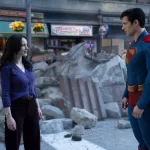 Imagem de Superman (David Corenswet) em uma pose heroica, com Lois Lane (Rachel Brosnahan) ao fundo, capturando a química entre os dois personagens no filme Superman, dirigido por James Gunn