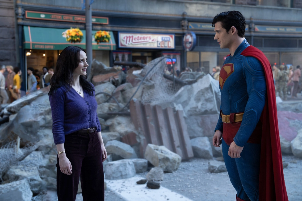 Imagem de Superman (David Corenswet) em uma pose heroica, com Lois Lane (Rachel Brosnahan) ao fundo, capturando a química entre os dois personagens no filme Superman, dirigido por James Gunn