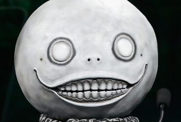 Yoko Taro usando sua icônica máscara de lua durante um evento da indústria de games.