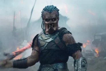 Predador segurando duas armas em posição de ataque no filme Predator: Badlands