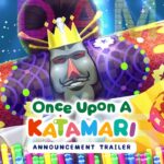 Imagem colorida do trailer de anúncio de 'Once Upon A Katamari', com o Rei do Cosmos, personagem principal da franquia, ao centro. Ele está usando uma coroa e rodeado por padrões vibrantes e elementos gráficos, como tubos coloridos e uma leque com símbolos japoneses. O nome do jogo aparece em letras grandes e coloridas no centro da imagem, com o texto 'Anúncio Trailer' abaixo.