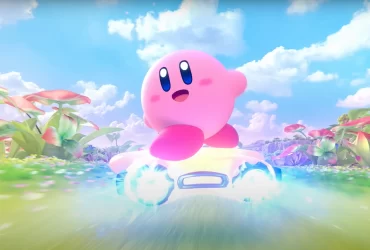 Kirby sorridente pilota uma estrela brilhante em alta velocidade por um campo florido, com céu azul e nuvens ao fundo.