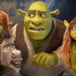 Cena animada de Shrek mostrando Shrek, Fiona, Burro e uma jovem ogra ruiva, todos com expressões de surpresa e apreensão, dentro de uma casa iluminada.