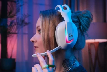 Mulher utilizando o headset sem fio Logitech G ASTRO A20 X LIGHTSPEED branco, com iluminação RGB ativada, em ambiente interno com iluminação azul e rosa.
