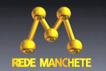 Logo clássico da Rede Manchete em dourado, exibido em fundo cinza, com a letra “M” formada por esferas conectadas.