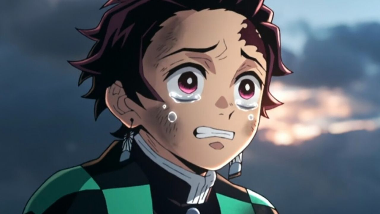 Close-up de Tanjiro Kamado, personagem de anime com cabelo preto avermelhado e brincos de hanafuda, chorando com lágrimas escorrendo pelo rosto e expressão de profunda tristeza, em cena do anime Demon Slayer