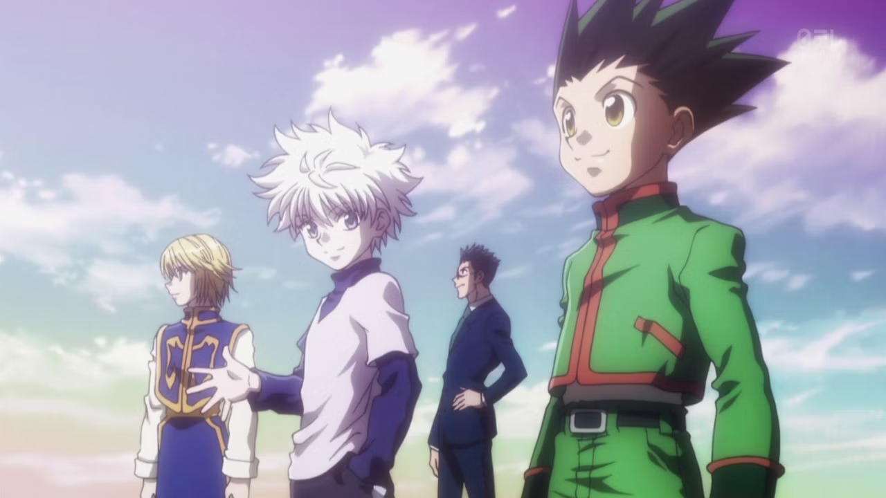 Quatro personagens de anime em pé sob céu azul com nuvens: à direita, jovem de cabelo preto espetado e jaqueta verde (Gon); ao centro-esquerda, jovem de cabelo branco prateado em roupas claras (Killua); ao fundo centro, homem adulto de terno escuro (Leorio); à esquerda, jovem de cabelo loiro e traje azul e dourado (Kurapika) - protagonistas de Hunter x Hunter