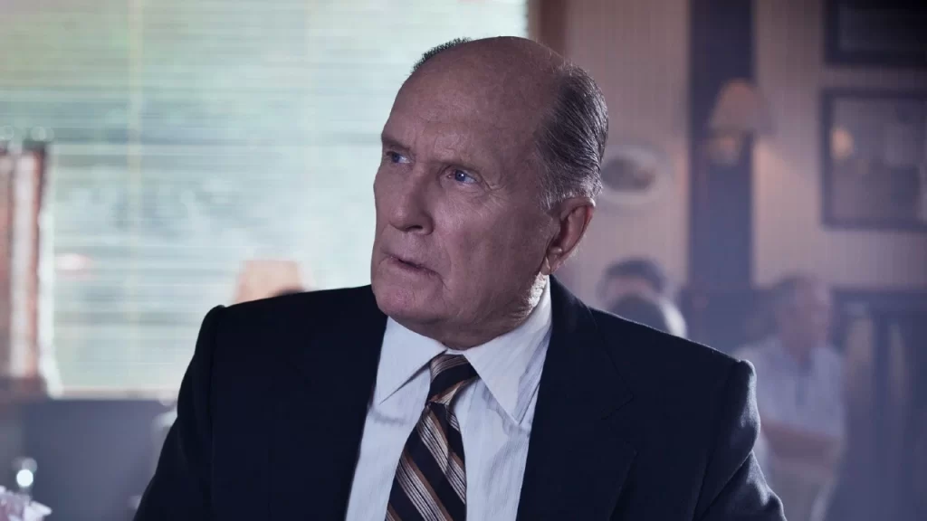 Robert Duvall, de terno escuro e gravata listrada, interpreta o juiz Joseph Palmer em cena do filme O Juiz, com expressão séria em um tribunal.