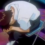 Shinji Ikari encolhido e chorando, abraçado às próprias pernas, sentado em uma cadeira metálica sobre um chão roxo, em cena de Neon Genesis Evangelion.