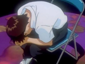 Shinji Ikari encolhido e chorando, abraçado às próprias pernas, sentado em uma cadeira metálica sobre um chão roxo, em cena de Neon Genesis Evangelion.