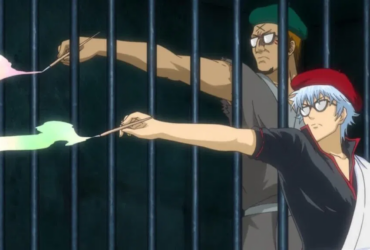 Cena de Gintama com dois personagens atrás de grades. Em primeiro plano, um personagem de cabelo prateado com boina vermelha aponta um pincel que solta um efeito de tinta clara. Ao fundo, outro personagem com óculos e boina verde faz o mesmo, em um cenário escuro.