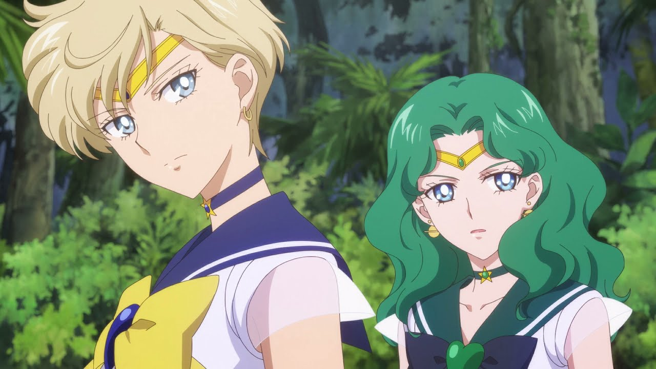 Cena de Sailor Moon com Haruka Tenou e Michiru Kaiou (Sailor Uranus e Sailor Neptune) em destaque, com expressões sérias e postura confiante, em um cenário externo com vegetação ao fundo.