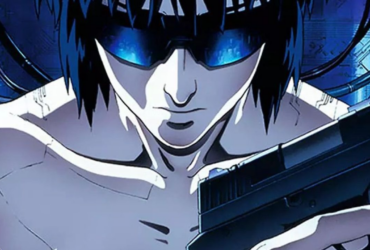 Personagem de Ghost in the Shell em close, com cabelo escuro e viseira azul brilhante, segurando uma arma em um cenário tecnológico de tons azuis, sugerindo introspecção e tensão.