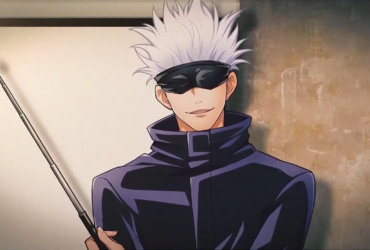 Gojo Satoru, de cabelo branco e usando uma venda preta nos olhos, sorri levemente enquanto segura uma haste apontadora; ele veste um casaco escuro de gola alta e está diante de um fundo claro com uma parede desgastada ao lado.
