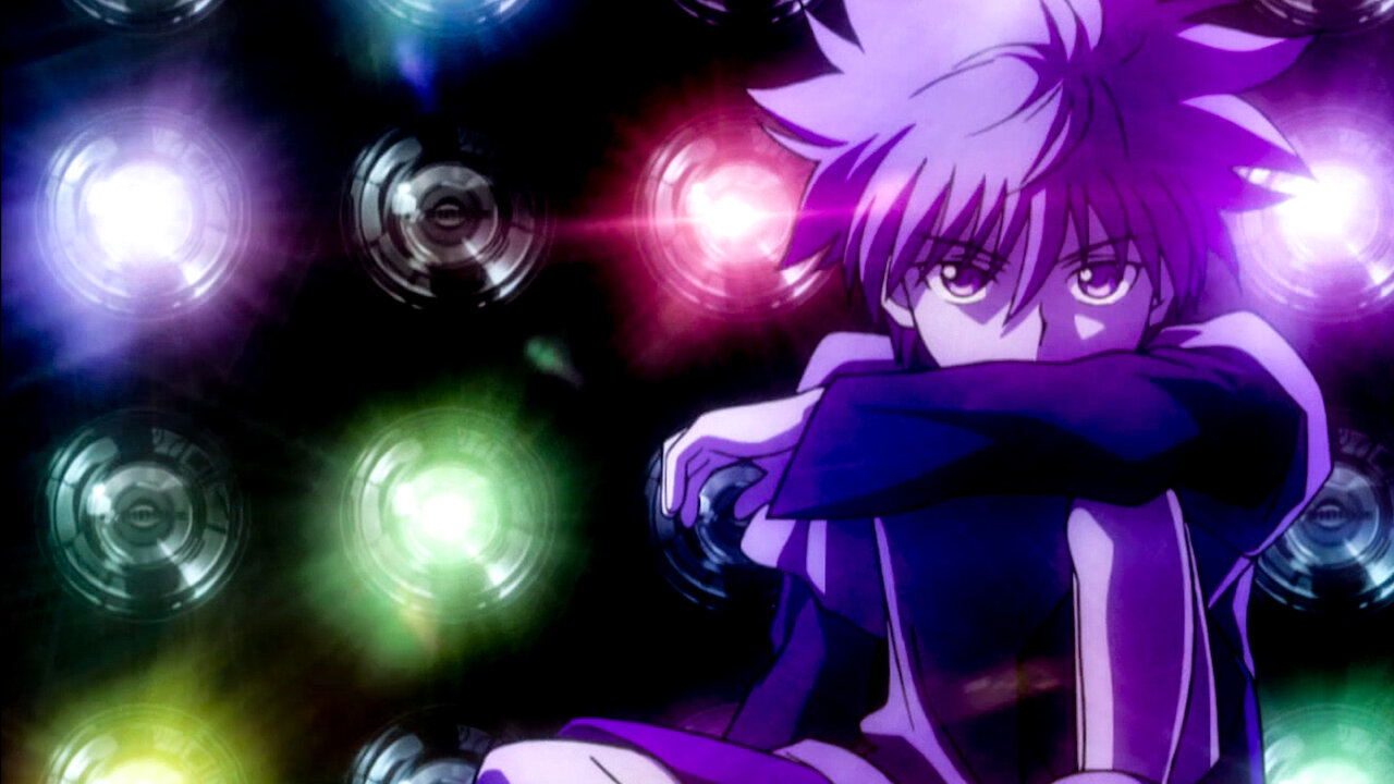 Killua Zoldyck, personagem de Hunter x Hunter com cabelo claro, sentado com os braços apoiados nos joelhos e olhar sério, cercado por luzes circulares coloridas (roxo, verde e vermelho) em um fundo escuro, criando um clima dramático e introspectivo.