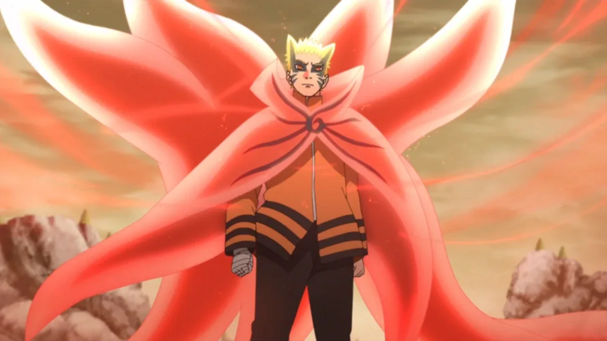 Naruto em pé no Modo Bárion, com capa e caudas de energia vermelha se abrindo atrás do corpo, expressão séria e fundo com céu alaranjado e rochas ao redor.