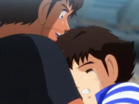 Cena de Captain Tsubasa (Super Campeões) em que Tsubasa, um garoto japonês emocionado e chorando, abraça Roberto, um homem brasileiro, em um estádio de futebol com arquibancadas desfocadas ao fundo. Imagem de Captain Tsubasa (Super Campeões) mostrando um japonês chorando nos braços de um brasileiro: Tsubasa abraça Roberto no estádio. A cena conversa com o clima de Brasil x Japão ao transformar rivalidade e contraste de estilos em algo mais humano — respeito, amizade e a vontade de “mais jogo” quando o apito final não basta.