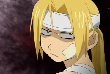 Edward Elric, protagonista de Fullmetal Alchemist: Brotherhood, aparece com o olhar tenso e expressão irritada, transmitindo nervosismo, firmeza e o peso de uma decisão difícil.