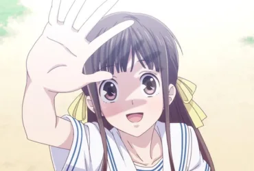 Tohru Honda, protagonista de Fruits Basket, aparece em primeiro plano sorrindo e levantando a mão diante do rosto, como se brincasse com a luz. Ela tem cabelos castanhos longos com laços amarelos e veste um uniforme escolar branco. O fundo claro e suave reforça a delicadeza, a alegria e a sensibilidade da personagem.