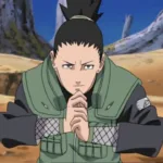 Shikamaru Nara, de Naruto, aparece agachado em uma área rochosa, com as mãos unidas em um selo ninja e expressão séria. Ele veste o colete verde de chunin e olha para frente de forma concentrada, enquanto o cenário de pedras e árvores reforça o clima de missão e estratégia.