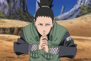 Shikamaru Nara, de Naruto, aparece agachado em uma área rochosa, com as mãos unidas em um selo ninja e expressão séria. Ele veste o colete verde de chunin e olha para frente de forma concentrada, enquanto o cenário de pedras e árvores reforça o clima de missão e estratégia.