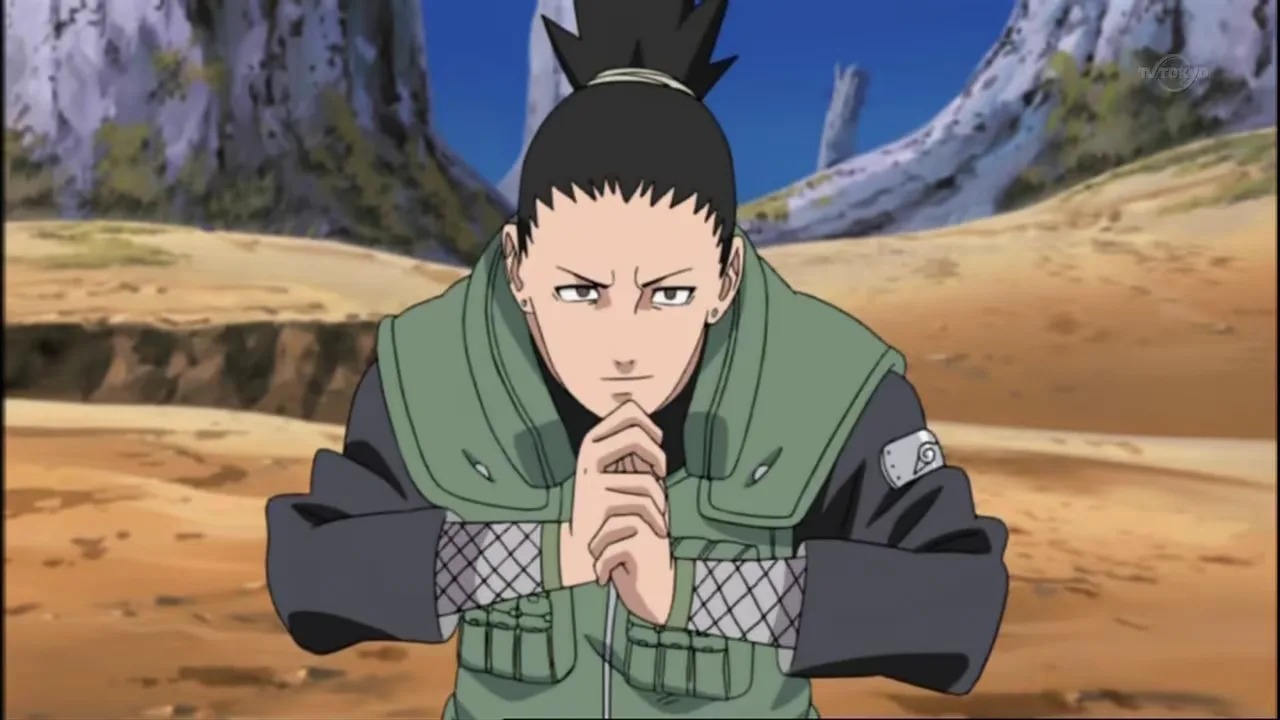 Shikamaru Nara, de Naruto, aparece agachado em uma área rochosa, com as mãos unidas em um selo ninja e expressão séria. Ele veste o colete verde de chunin e olha para frente de forma concentrada, enquanto o cenário de pedras e árvores reforça o clima de missão e estratégia.