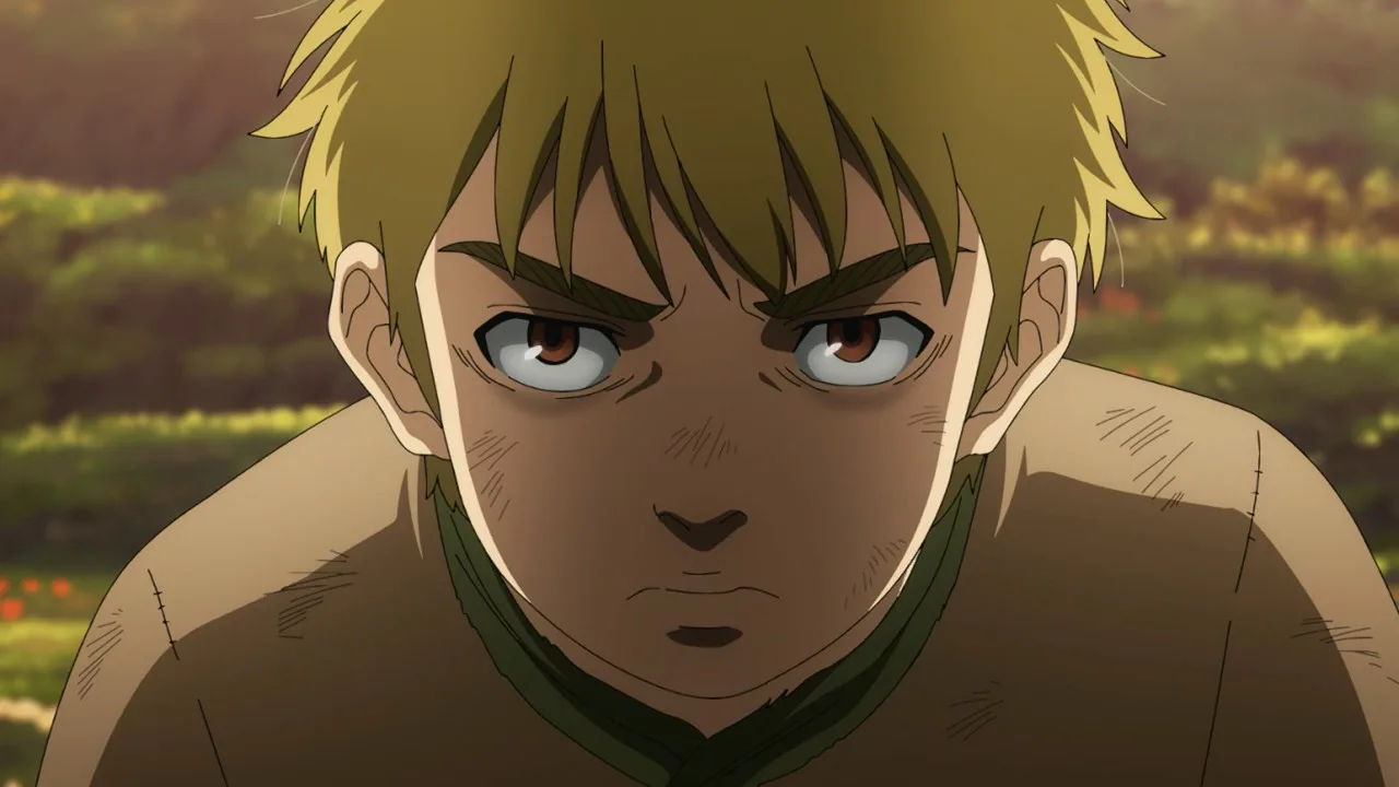 Thorfinn criança, personagem de Vinland Saga, aparece em close com expressão séria e determinada. Seus cabelos loiros estão desalinhados, há marcas de sujeira e pequenos ferimentos em seu rosto e roupas, e o cenário externo desfocado em tons quentes reforça o clima de jornada, conflito e alerta constante.