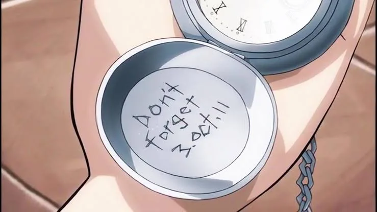 Mão segura o relógio de bolso prateado de Edward Elric aberto, com a inscrição “Don’t Forget 3.Oct.11” gravada na parte interna da tampa.